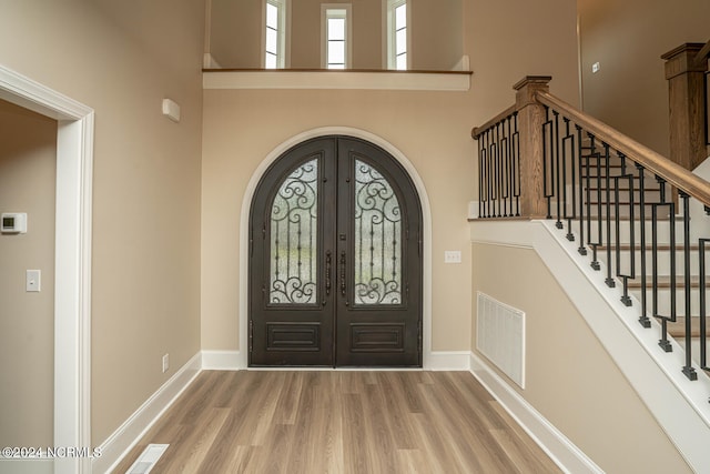 foyer with arched walkways, french doors, visible vents, and wood finished floors