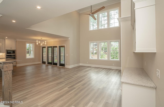 unfurnished living room with baseboards, a healthy amount of sunlight, light wood-type flooring, and crown molding