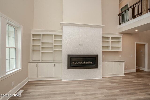 unfurnished living room featuring light wood-type flooring and a high ceiling