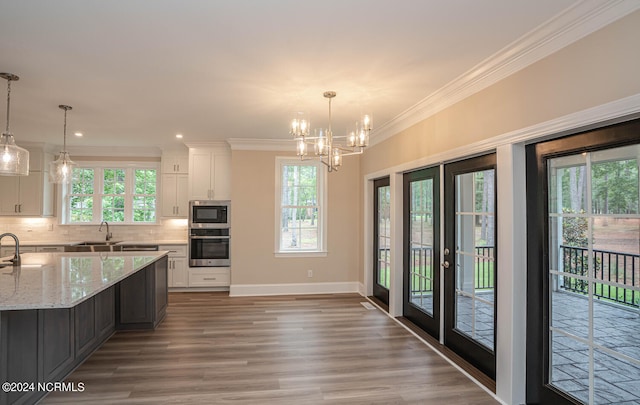 kitchen featuring light stone counters, stainless steel appliances, white cabinets, ornamental molding, and tasteful backsplash