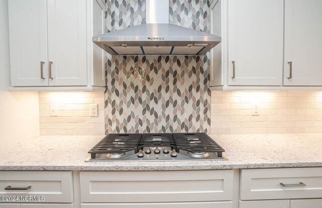 kitchen with light stone countertops, tasteful backsplash, stainless steel gas stovetop, and wall chimney range hood