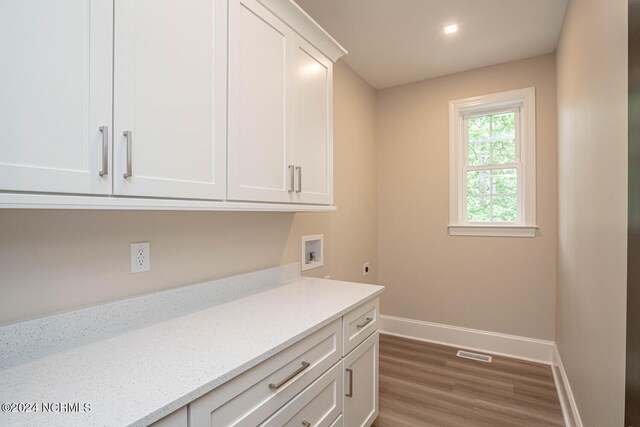 laundry area featuring hookup for an electric dryer, hardwood / wood-style flooring, washer hookup, and cabinets