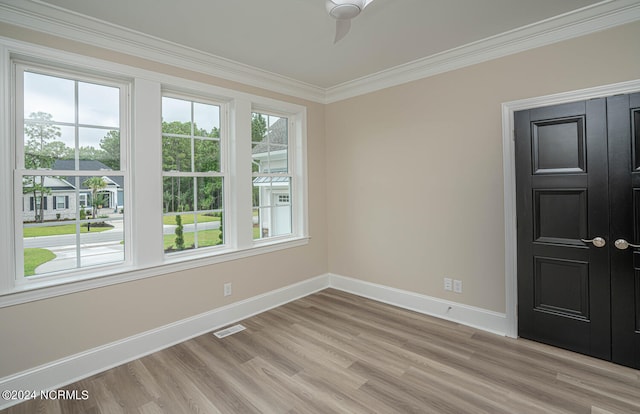 spare room with light wood finished floors, ornamental molding, visible vents, and baseboards