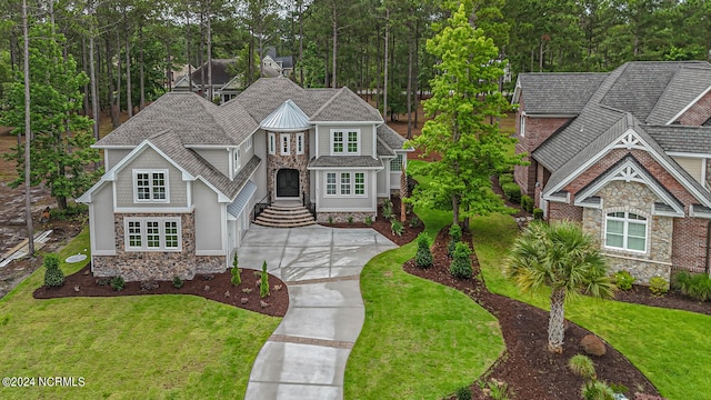 craftsman inspired home with driveway, stone siding, roof with shingles, and a front yard