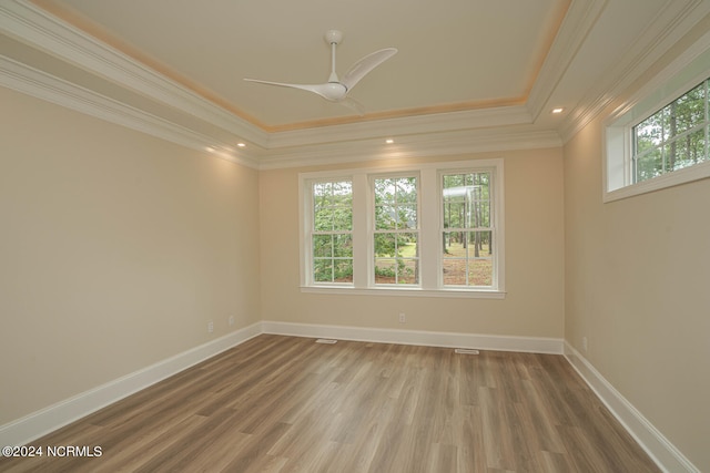 spare room featuring a tray ceiling, ceiling fan, crown molding, and hardwood / wood-style flooring