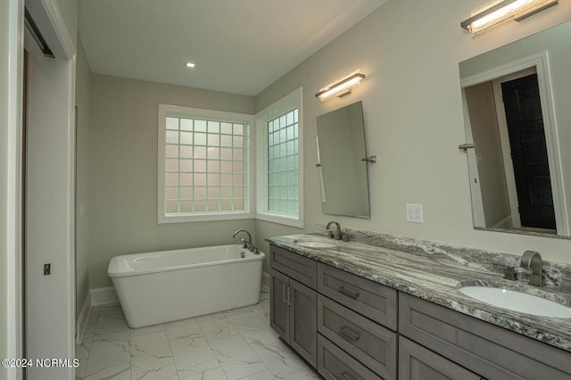 bathroom with a freestanding tub, marble finish floor, a sink, and double vanity