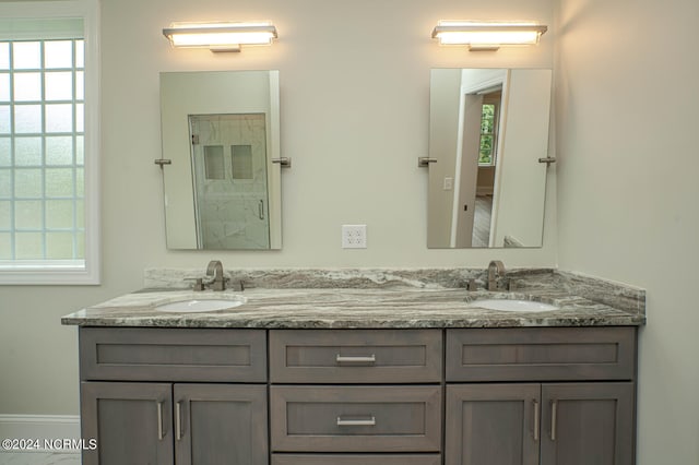 full bath with a healthy amount of sunlight, double vanity, and a sink