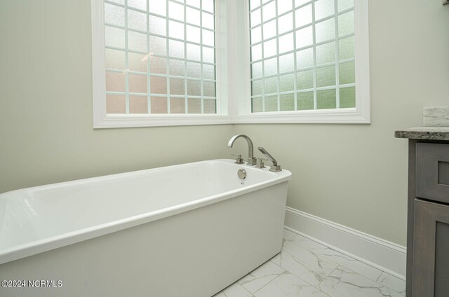 bathroom featuring tile patterned flooring, a bathtub, and vanity