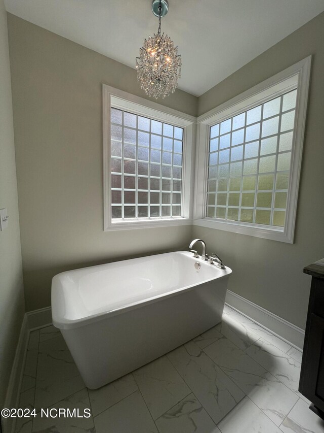 bathroom with an inviting chandelier, a tub to relax in, tile patterned floors, and vanity