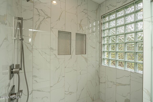 bathroom with a marble finish shower and a healthy amount of sunlight