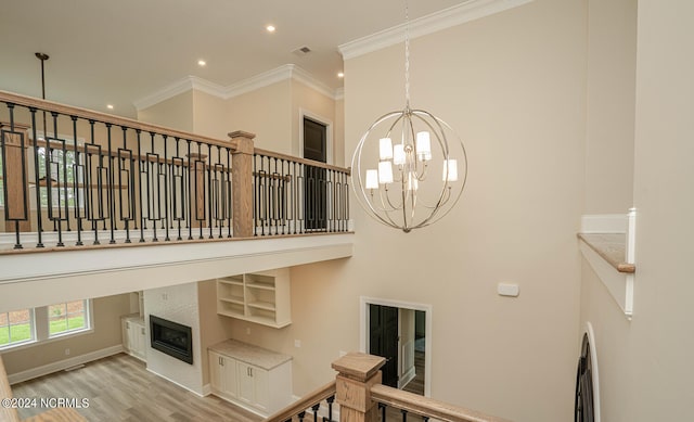 interior space featuring a towering ceiling, crown molding, an inviting chandelier, and light hardwood / wood-style floors