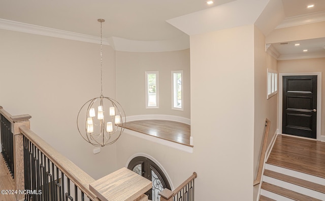 stairway with baseboards, wood finished floors, an inviting chandelier, crown molding, and recessed lighting