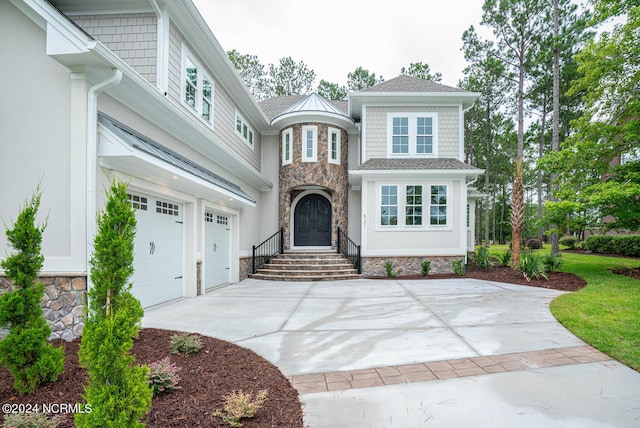 view of front of home featuring stone siding, an attached garage, and concrete driveway