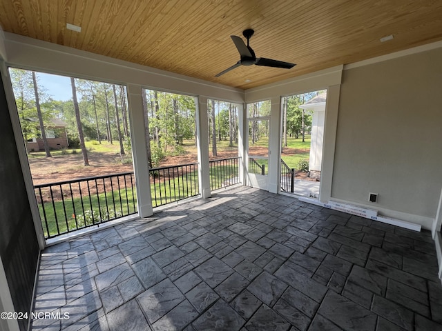 unfurnished sunroom featuring wooden ceiling and a ceiling fan