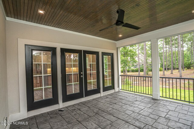 unfurnished sunroom featuring wooden ceiling, french doors, ceiling fan, and a healthy amount of sunlight