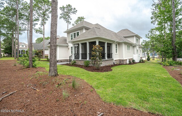 view of side of property with a sunroom and a yard