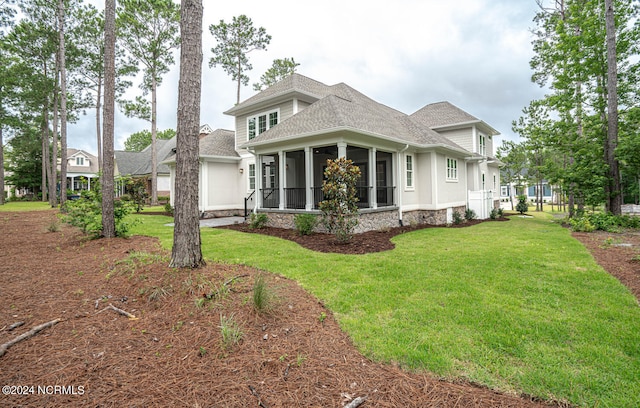 exterior space featuring a shingled roof, a front yard, and a sunroom