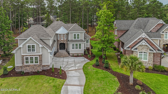 craftsman-style home with stone siding, a front lawn, and concrete driveway