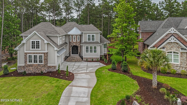 view of front of home featuring stone siding, roof with shingles, concrete driveway, and a front yard