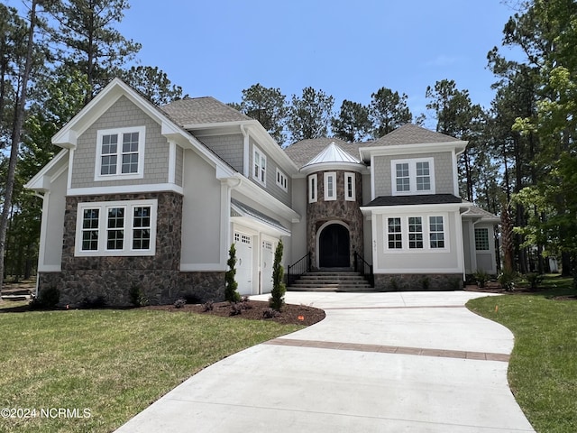 view of front of home featuring a shingled roof, concrete driveway, an attached garage, a front yard, and stone siding