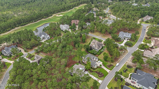 drone / aerial view with golf course view, a water view, a wooded view, and a residential view