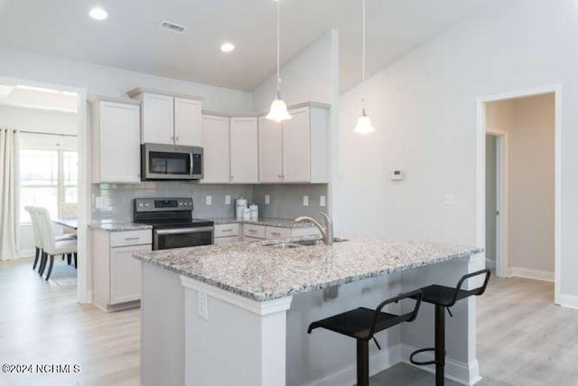 kitchen with appliances with stainless steel finishes, backsplash, light wood-type flooring, and hanging light fixtures