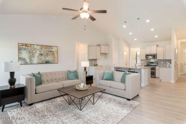 living room featuring high vaulted ceiling, light hardwood / wood-style flooring, and ceiling fan