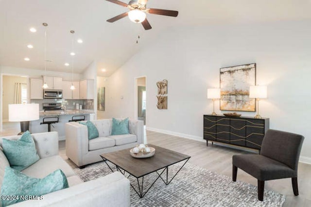 living room featuring high vaulted ceiling, light hardwood / wood-style flooring, and ceiling fan