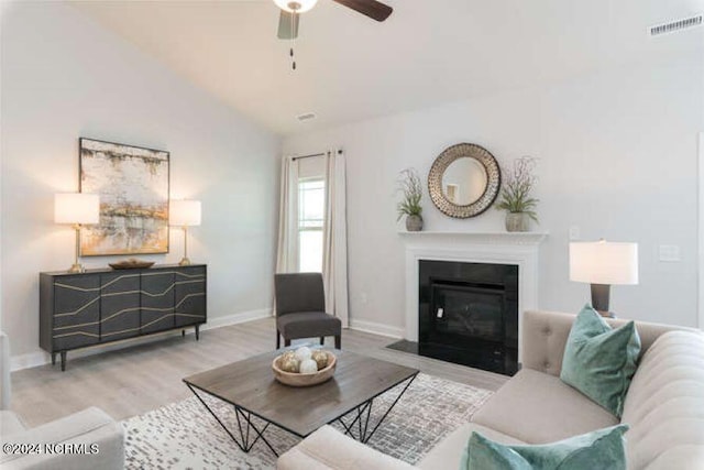 living room featuring ceiling fan, vaulted ceiling, and light wood-type flooring