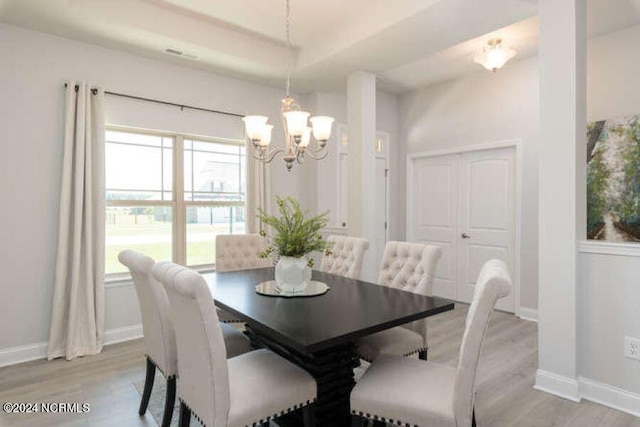 dining room with a notable chandelier, light hardwood / wood-style floors, and a tray ceiling