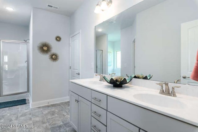 bathroom featuring a shower with shower door, tile floors, and double vanity