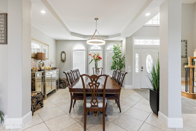 dining space featuring a raised ceiling and light tile flooring