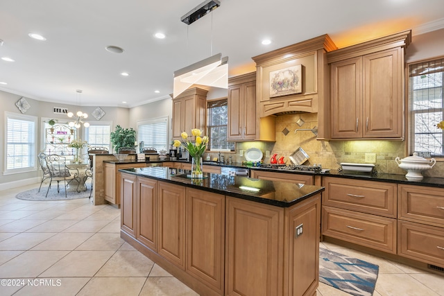 kitchen with pendant lighting, a center island, a notable chandelier, backsplash, and dark stone countertops