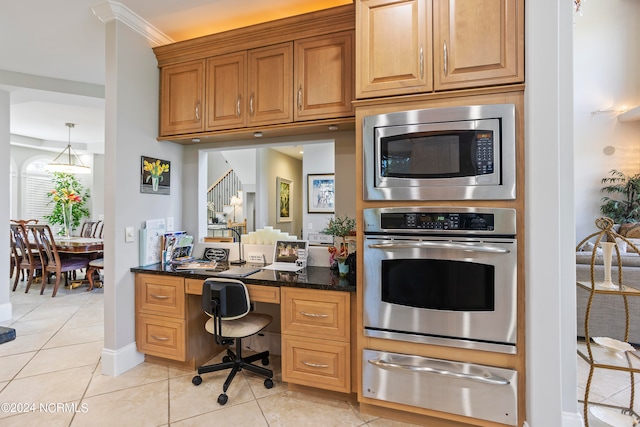 kitchen featuring hanging light fixtures, dark stone counters, stainless steel appliances, light tile floors, and crown molding