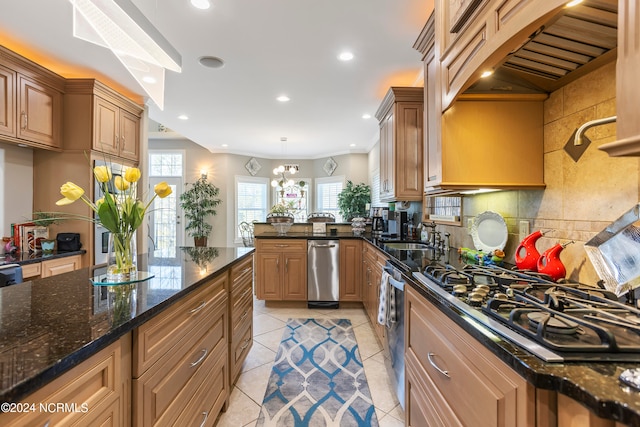 kitchen featuring a chandelier, light tile flooring, appliances with stainless steel finishes, backsplash, and dark stone countertops