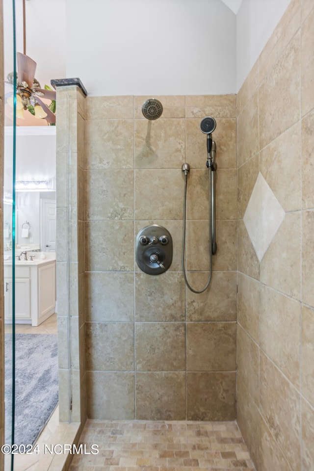 bathroom with a tile shower, ceiling fan, and sink