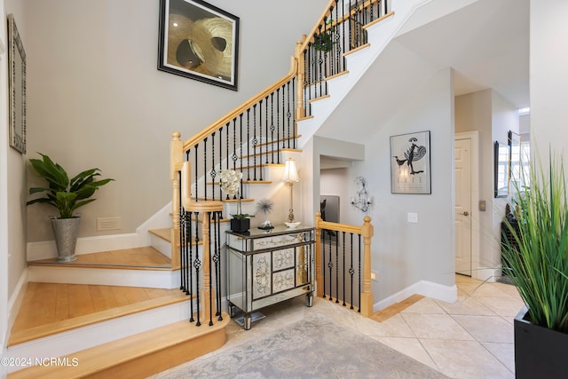 staircase featuring a towering ceiling and light tile floors