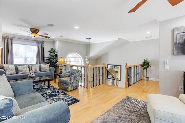 living room featuring crown molding, light hardwood / wood-style floors, and ceiling fan with notable chandelier