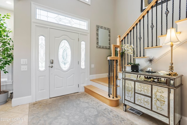 tiled foyer with a towering ceiling and a wealth of natural light