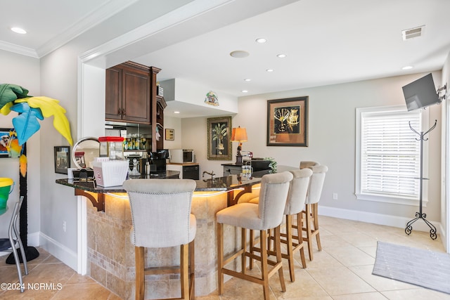 kitchen with kitchen peninsula, a kitchen bar, and light tile floors