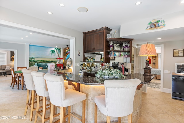 kitchen featuring light tile flooring, dark brown cabinets, a breakfast bar area, and dishwasher