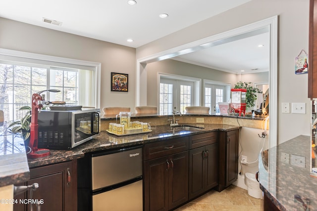 kitchen with dark stone counters, french doors, dark brown cabinets, stainless steel appliances, and light tile flooring