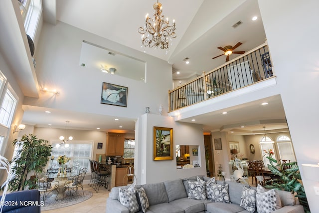 tiled living room with high vaulted ceiling, ceiling fan with notable chandelier, and a healthy amount of sunlight