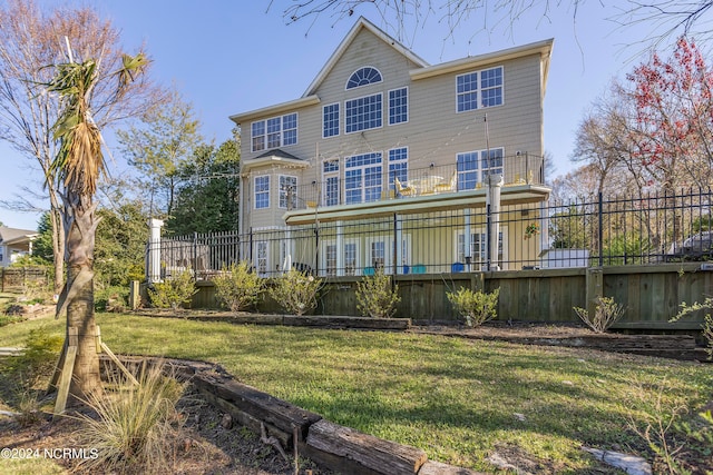 rear view of house featuring a balcony and a yard