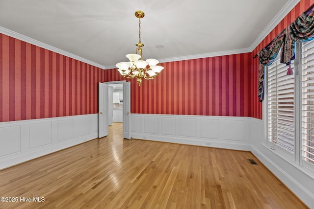 unfurnished dining area featuring crown molding, an inviting chandelier, and hardwood / wood-style floors