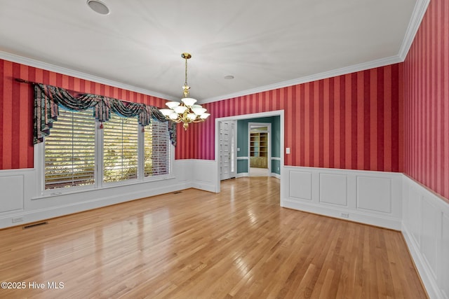 unfurnished dining area featuring an inviting chandelier, hardwood / wood-style flooring, and ornamental molding