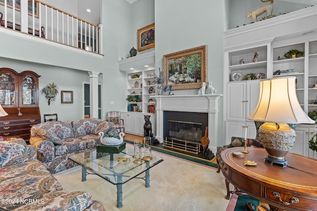 carpeted living room featuring a towering ceiling, built in shelves, and decorative columns