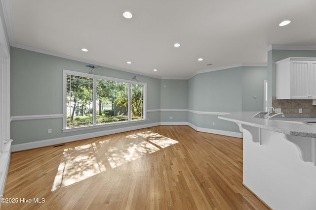 unfurnished living room featuring light wood-type flooring and ornamental molding