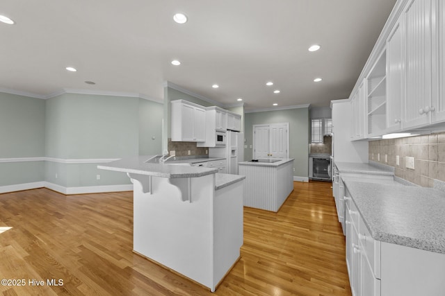 kitchen featuring white appliances, light hardwood / wood-style floors, white cabinetry, and kitchen peninsula