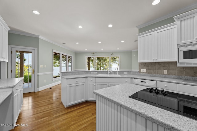 kitchen with ornamental molding, sink, white appliances, and white cabinetry